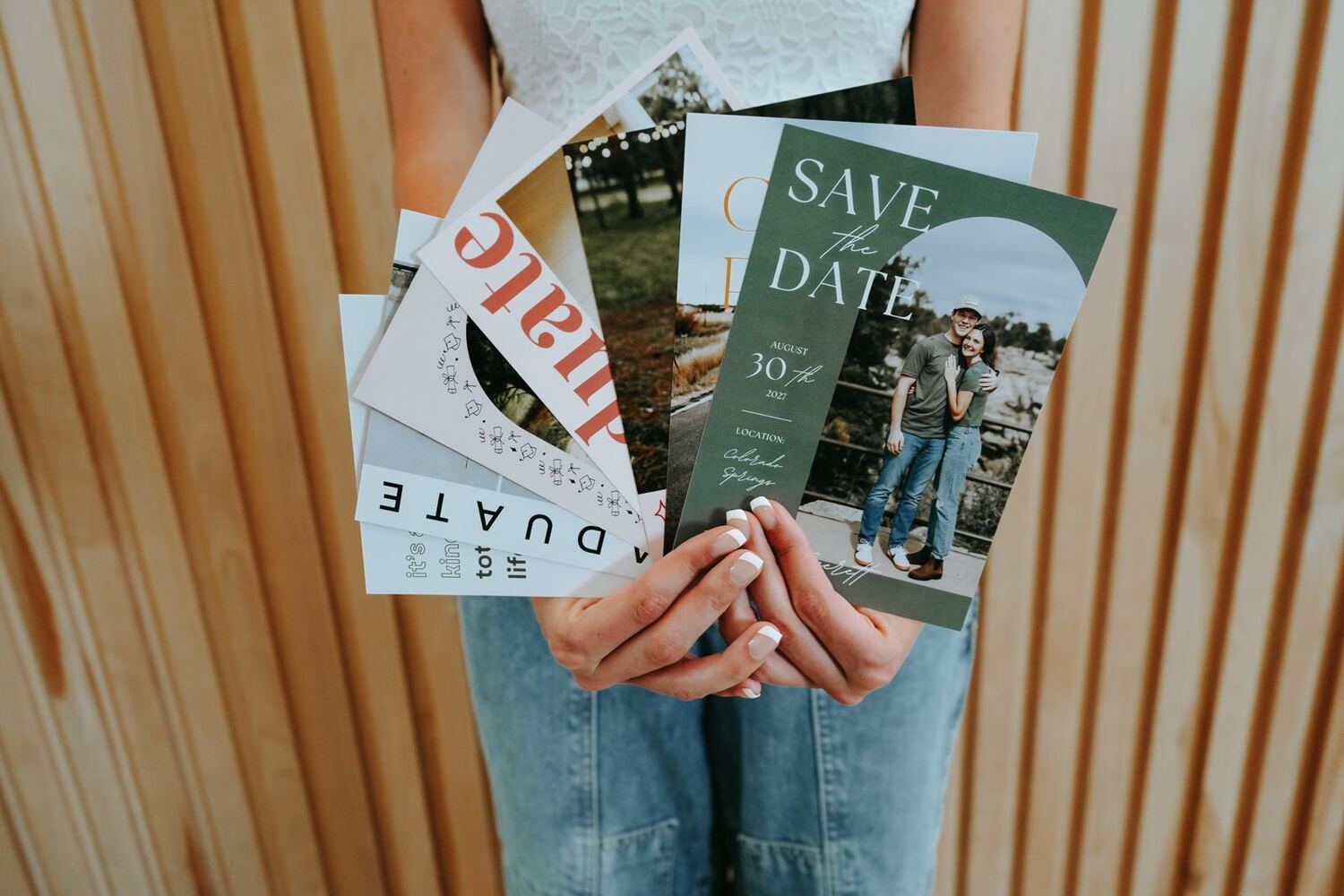 Hunter holding a fan of custom cards and a green save the date