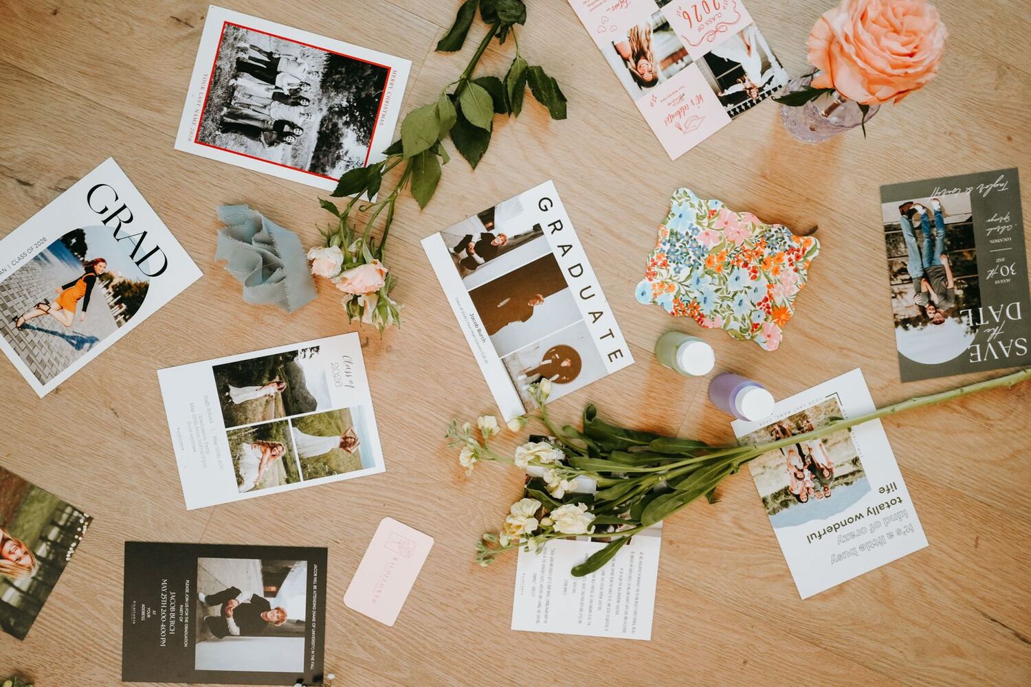 Custom graduation cards and announcements spread on a wood table with peach roses