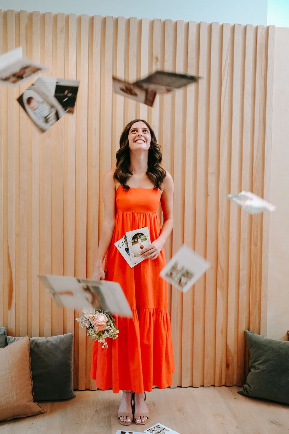 Hunter in an orange dress laughing as her cards fly through the air