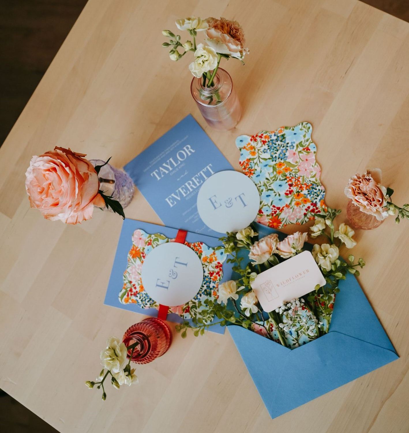 Three-piece wedding suite: invitation, floral details card and monogram RSVP tag with a blue envelope