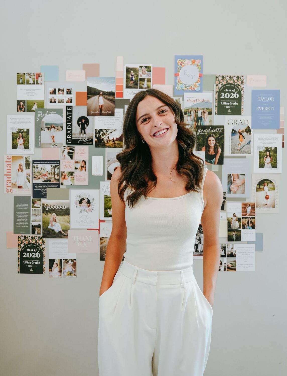 Hunter smiling in front of a wall of her card designs